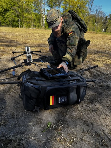 Operator preparing AERIS Recon S7 with a mobile transport bag and ground control station for field deployment.