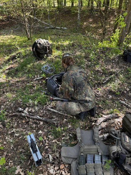 Operator preparing AERIS Recon S7 with transport bag and system components for mobile deployment in wooded terrain.